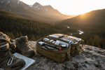 Adventure first aid kit essentials packed in a sturdy bag beside hiking boots on a rocky terrain.