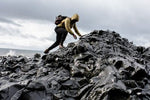 Preventing and Treating Fall Injuries in Slippery Terrain with a hiker climbing rocky formations near the ocean.