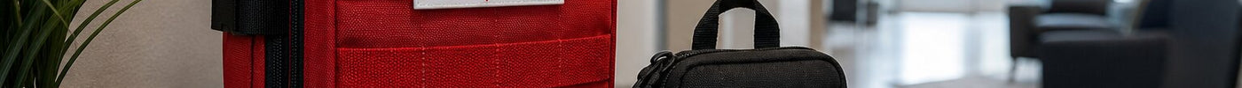 Red and black ViTAC bleed control kits for emergencies on a wooden table in a modern indoor setting.