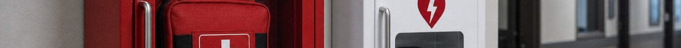 Wall-mounted bleed control station with AED unit in an institutional setting — stop-the-bleed kit components and placement guide
