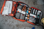 TCCC compliant trauma kits featuring organized medical supplies in red bags on a gray surface.