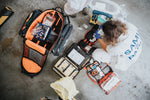 A person organizing family emergency trauma kits laid out on a floor, demonstrating preparedness for emergencies.
