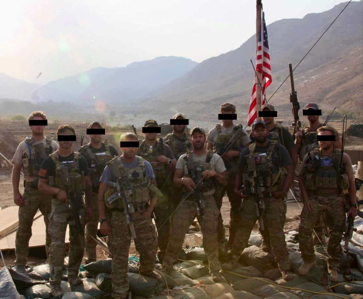 Group of soldiers in military gear with an American flag in a desert setting