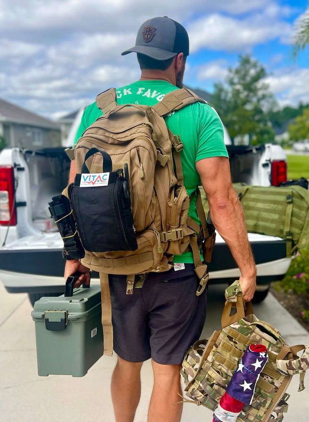 Man carrying a tactical backpack and equipment, showcasing the ViTAC Tactical Individual First Aid Kit for emergency medical support.