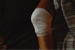 A knee covered with traditional gauze, contrasting with hemostatic gauze used for emergencies.