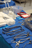 A collection of surgical tools and gauze laid out on a blue surgical table for emergency procedures.