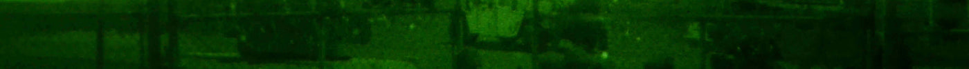 What is a Green Beret training under night vision with soldiers and equipment in the background.