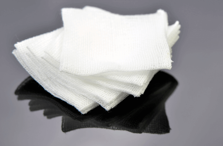Stack of white Non-Adherent Pads on a reflective surface, essential for effective wound care in emergencies.