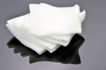 Stack of white Non-Adherent Pads on a reflective surface, essential for effective wound care in emergencies.