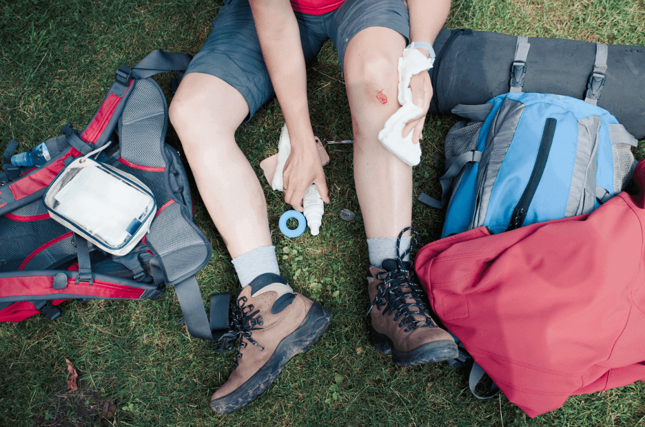 How QuikClot Gauze being used for quick bleeding control on an injured leg outdoors with hiking gear.