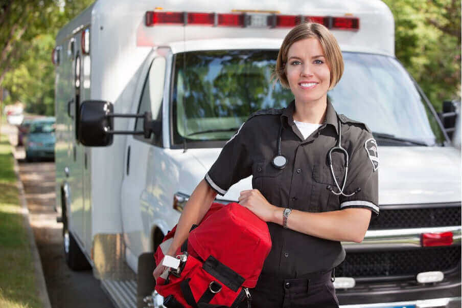 First Aid Training: Why Advanced Medical Skills Are Essential for Preparedness - EMT standing by ambulance with medical bag.