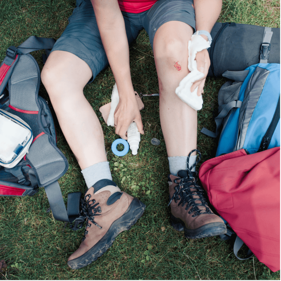 Trailside Heroes: Mastering First Aid for Cuts, Scrapes, and Wounds being applied on a wounded leg outdoors.