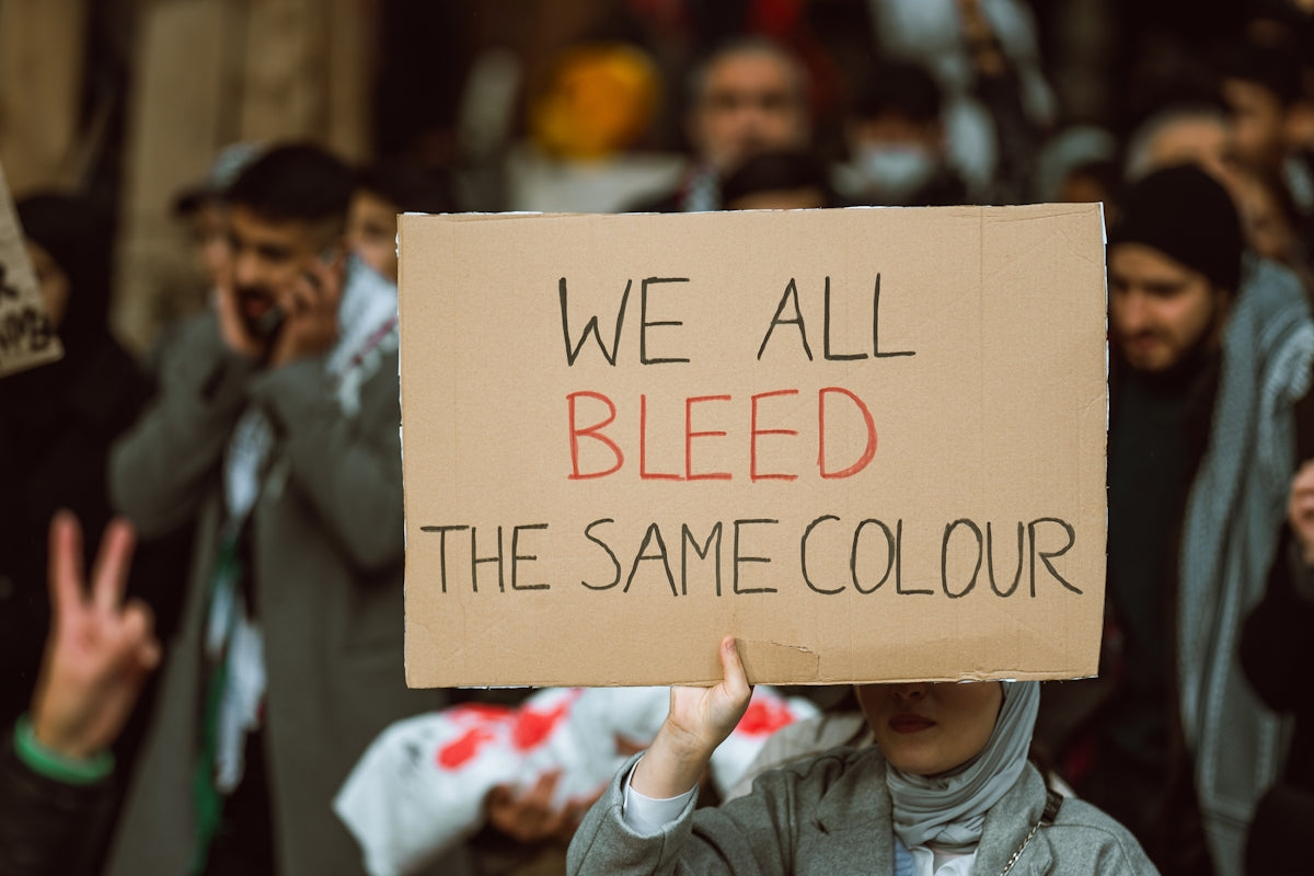 A person holding a sign that says we all bleed the same color