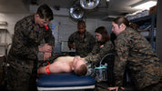 Soldiers providing medical care using a tactical IFAK trauma kit in a military setting.