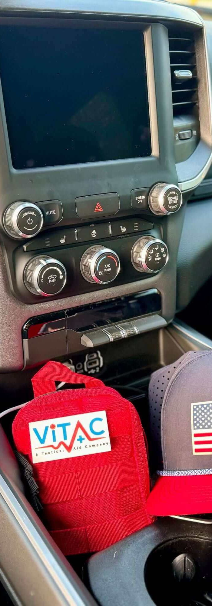 Everyday Carry EDC Kit displayed in a vehicle center console with a red pouch and American flag cap.