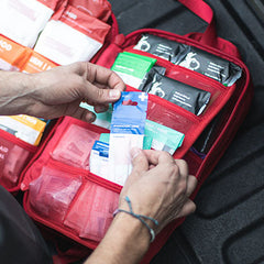 Person organizing items in the MyFAK Large Medical Kit by MyMedic, showing various medical supplies.