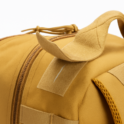 Close-up of tactical trauma backpack handle and zipper section in yellow, showcasing durable materials.