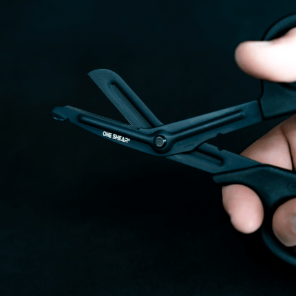 Lightweight medical scissors for EMT held in hand featuring black fluoride non stick coating and blunt tip for safety.
