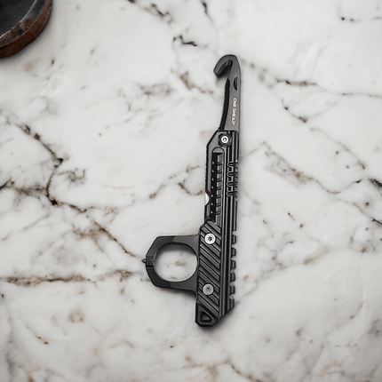 3-in-1 rescue tool shown on marble surface, featuring seatbelt cutter, window breaker, and knuckle protector.