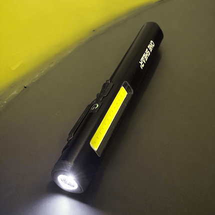 ONE SHEAR® XPE+COB USB-C rechargeable magnetic penlight on a dark surface with bright lighting.