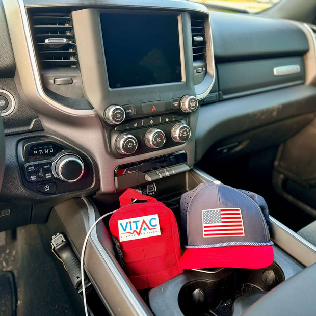 ViTAC EDC Trauma Kit and cap displayed in a vehicle's center console, emphasizing readiness on the go.