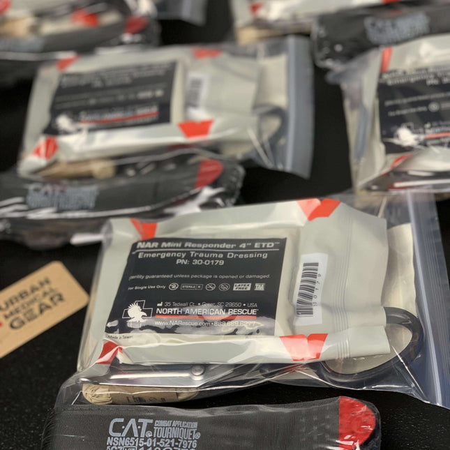 Compact emergency medical kit contents including CAT tourniquet and trauma dressing packages.