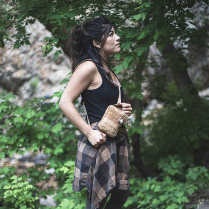 Woman wearing Sidekick IFAK Pouch by MyMedic in a natural setting, showcasing its compact design.