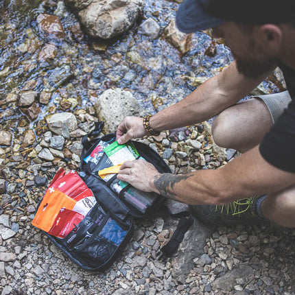 MyFAK First Aid Kit opened beside a river, showing various medical supplies for emergency care.