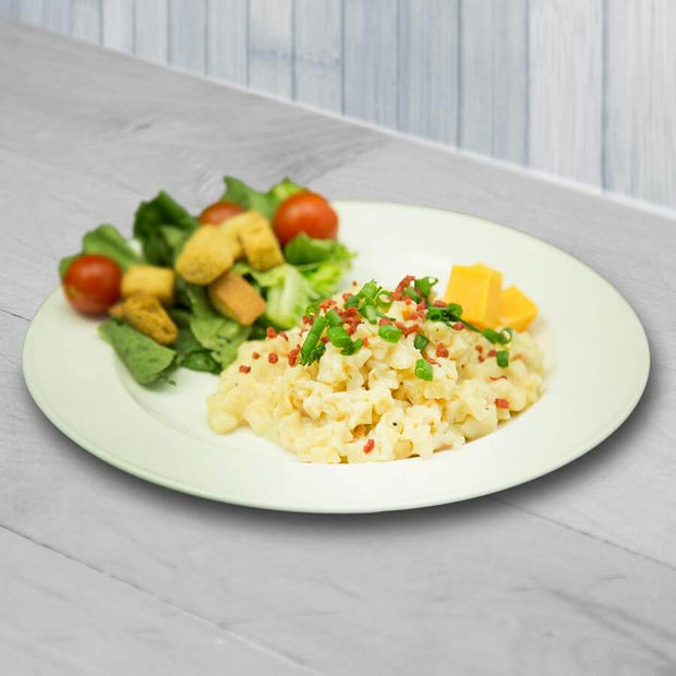 Plate of creamy pasta with green onions, side salad with tomatoes and croutons, and cheese cubes.